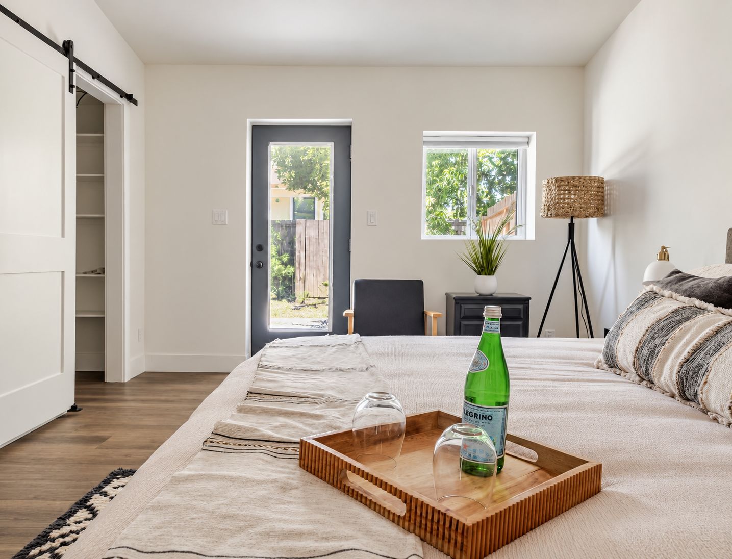 Une chambre à coucher avec un lit, une table de chevet avec une lampe, une fenêtre et une porte coulissante donnant sur un balcon.