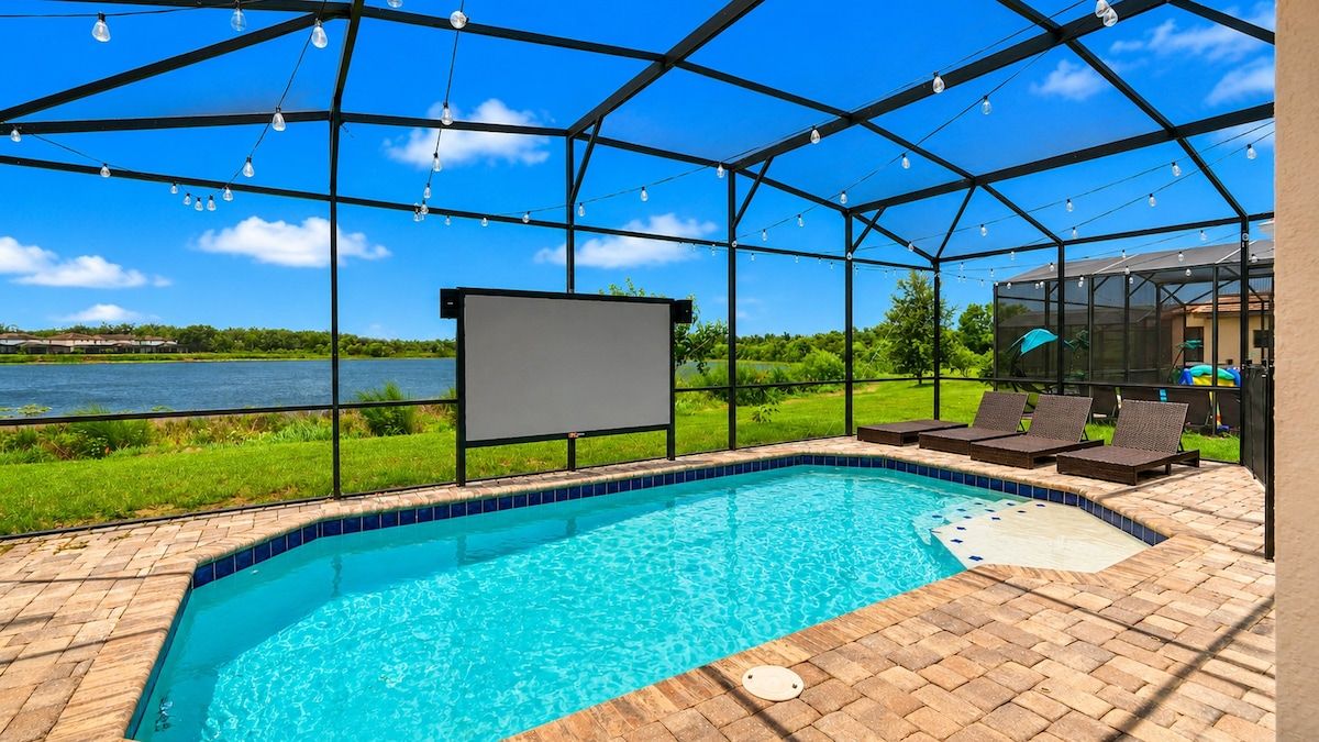 A swimming pool with a glass enclosure, a whiteboard, and lounge chairs.