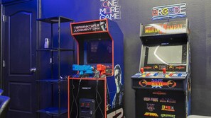 Arcade machines, including Terminator 2 Judgment Day and Mortal Kombat, in a room with a dark blue door and a neon sign. - 4BR Themed Villa Pool & Cinema Balmoral Resort (Haines City)