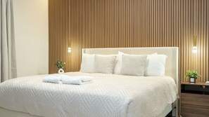 Ein Hotelzimmer mit einem großen Bett, einer Wand aus Holzleisten und zwei Nachttischen mit Lampen.