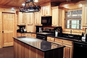 A kitchen with wooden cabinets, a black countertop, and a stove. - Heated Pool/Cinema/Hot Tub/Game Room/Massage Chair (Broken Bow)