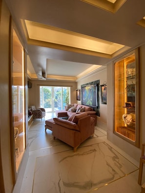 A spacious living room with a large sectional sofa, a flat-screen TV mounted on the wall, and a glass display cabinet with decorative items. - Poirot Oporto Apartment (Porto)