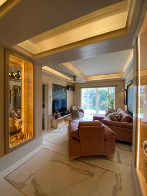 A spacious living room with a large flat-screen TV, a sofa set, and a decorative glass cabinet. - Poirot Oporto Apartment (Porto)