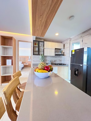 A modern kitchen with a central island, wooden cabinets, and a built-in microwave.