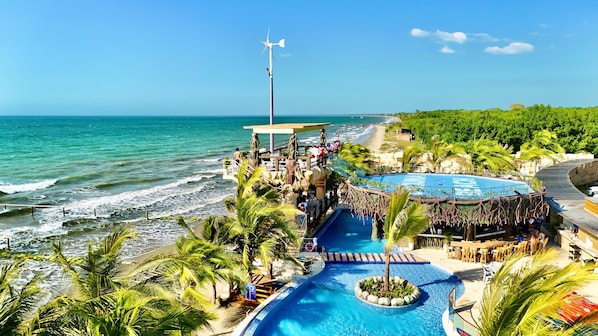 A resort with a pool, beach access, and a wind turbine.