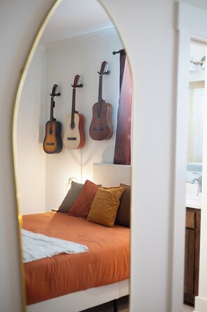 Ein Schlafzimmer mit einem Bett, Kissen und drei an der Wand befestigten Gitarren.