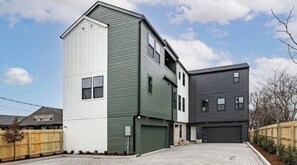 En tvåvånings bostadsbyggnad med ett garage, en uppfart och ett trästaket.