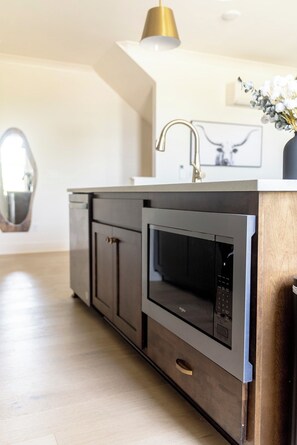 Une cuisine moderne équipée d’un four à micro-ondes encastré, d’un évier et d’un meuble de rangement.