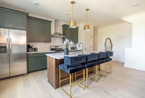 A modern kitchen with a central island, stainless steel appliances, and a bar seating area. - Nashville Getaway - Sleeps 8 - 9 Min to Broadway (Nashville)