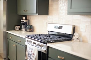 Une cuisine équipée d’une cuisinière à gaz, d’une machine à café et d’une pancarte sur laquelle on peut lire « Bienvenue ».