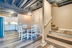 A modern kitchen with white cabinets, a dining table with chairs, and a staircase with wooden steps. - Scenic Lake Getaway: Private Sauna & Beach Access (Greenfield Township)