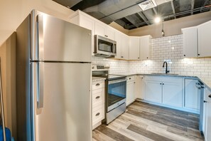 A modern kitchen with white cabinetry, stainless steel appliances, a microwave, oven, and a sink. - Scenic Lake Getaway: Private Sauna & Beach Access (Greenfield Township)