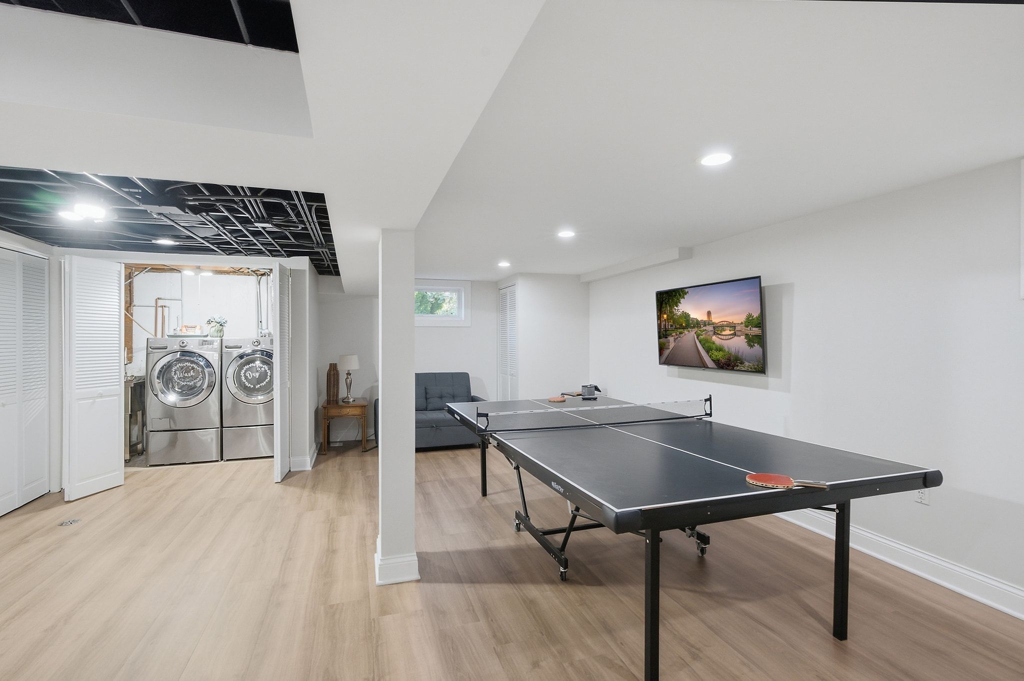 Un intérieur moderne avec une table de ping-pong, un lave-linge et un tableau accroché au mur.