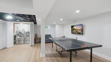 Un intérieur moderne avec une table de ping-pong, un lave-linge et un tableau accroché au mur.