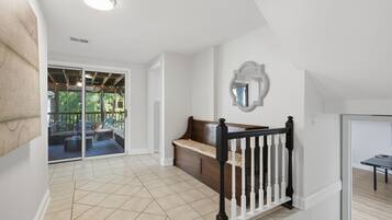 A spacious hallway with a wooden bench, a mirror on the wall, and a view into a patio area.