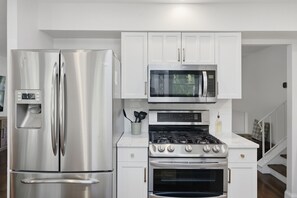 A compact kitchen with a stainless steel refrigerator, a microwave, and a gas stove.