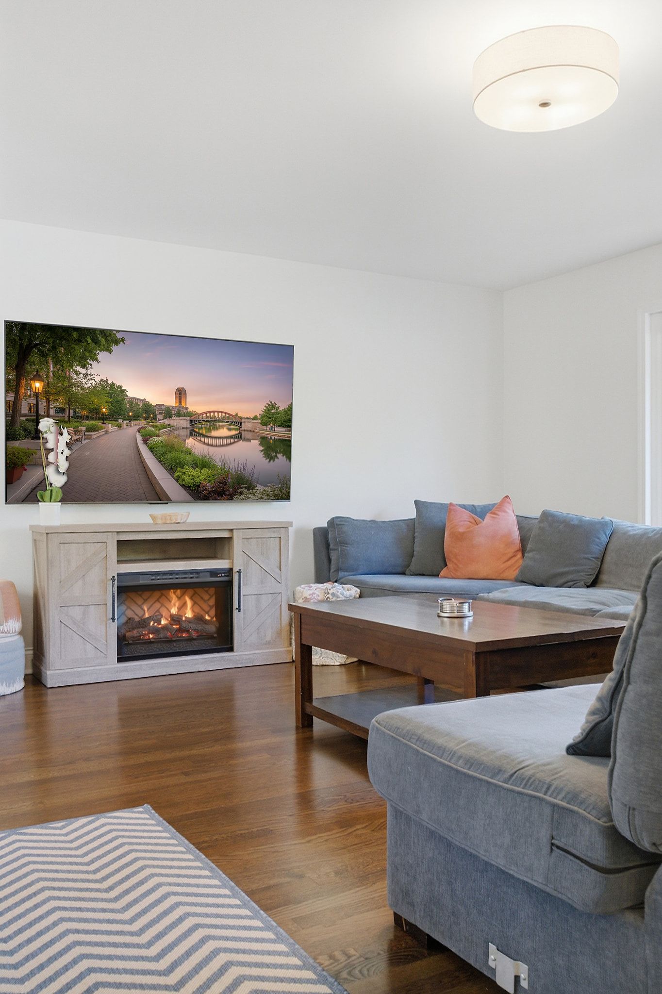 Een moderne woonkamer met een open haard, een bank, een salontafel en een grote flatscreen-televisie aan de muur.