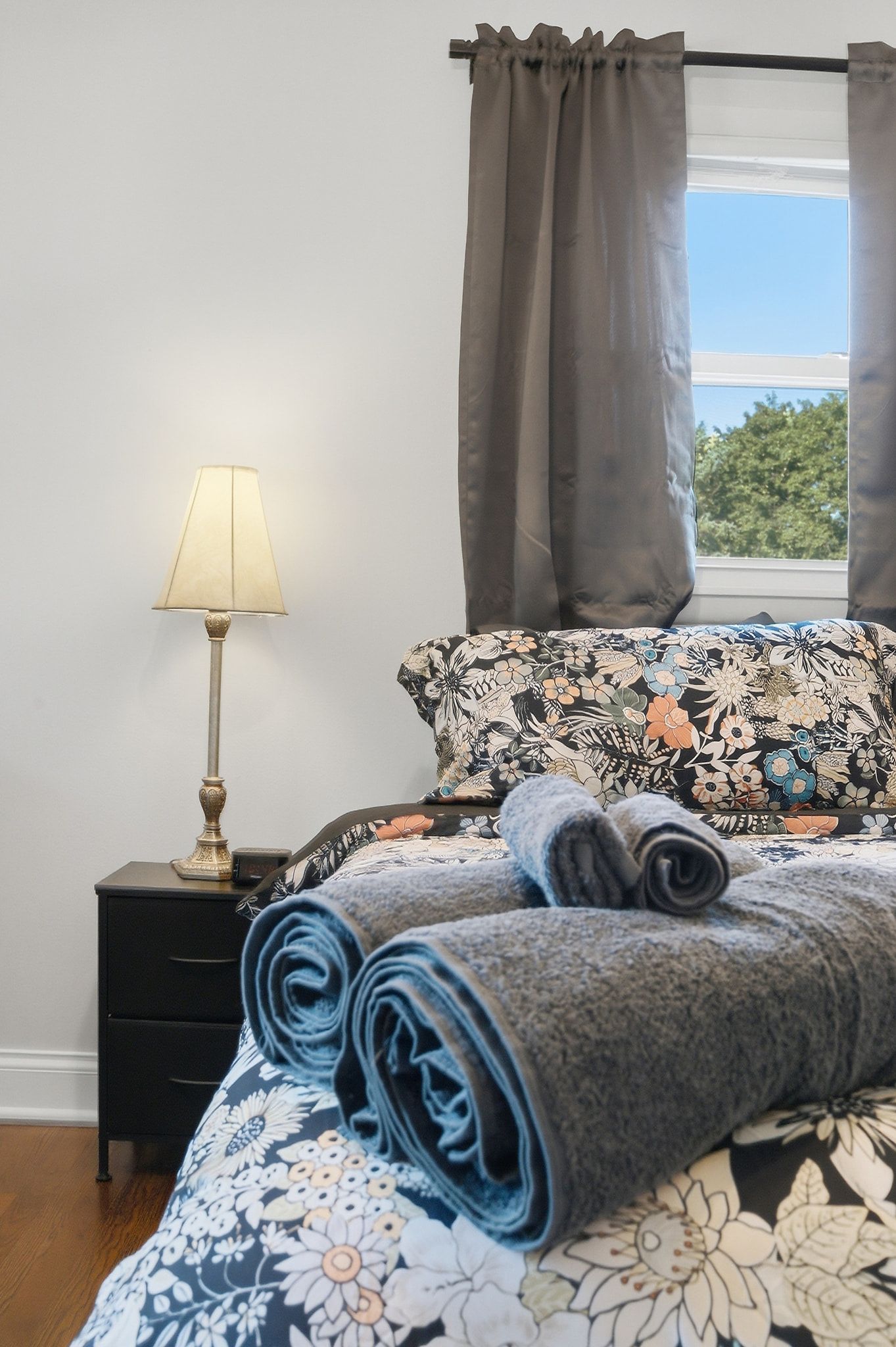 Une chambre à coucher avec un lit, une table de chevet, une lampe et une fenêtre avec des rideaux.