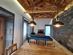 Ein Essbereich mit einem Holztisch und Stühlen, einer Steinwand und einem Fernseher im Hintergrund.