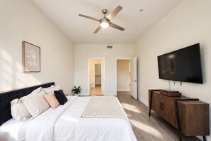 Ein Schlafzimmer mit einem Bett, einem Deckenventilator, einem Fernseher und einem Holzkasten.