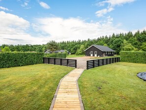 A wooden pathway leading to a building with a dark roof, surrounded by well-maintained grass and hedges. - "Tobias" - 30km from the sea by Interhome (Toftlund)