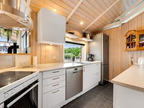 Een moderne keuken met witte kasten, roestvrijstalen apparatuur en uitzicht op de omgeving.