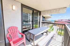 A balcony with a table and chairs, a view of a building, and a clear sky. - Sea Watch 119 (Ocean City)