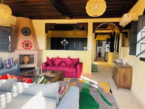 Uma sala de estar com lareira, sofá, mesa de centro e tapete estampado.