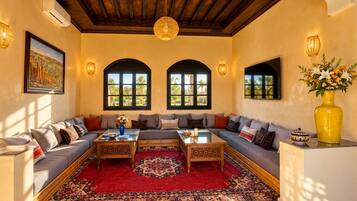 Ein geräumiges Wohnzimmer mit einer großen L-förmigen Couch, einem Couchtisch und einem roten Teppich mit Muster.
