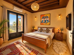 A bedroom with a large bed, a balcony with a view, and a painting on the wall.