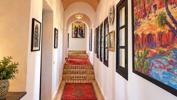 A hallway with a tiled floor, a red carpet, and a painting on the wall.