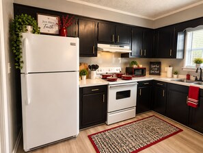 A kitchen with dark cabinets, a white refrigerator, a stove, and a microwave.