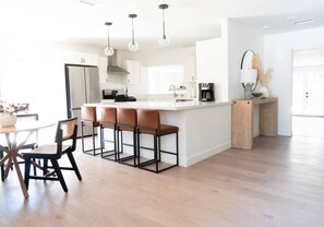 A modern kitchen with a central island, bar stools, and pendant lighting.