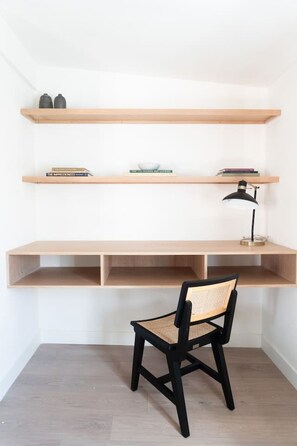 A workspace with a desk, chair, shelves, and a lamp.
