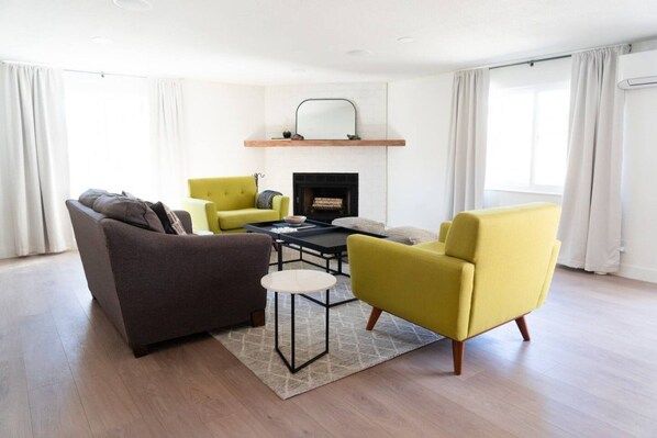 A modern living room with a fireplace, a sofa, two armchairs, and a coffee table.