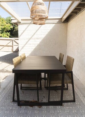 Un patio con mesa y sillas, un lámpara colgante y vistas del entorno.