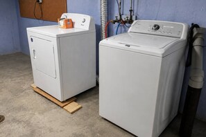 Two front-loading washing machines in a laundry room with a wooden floor and blue walls.