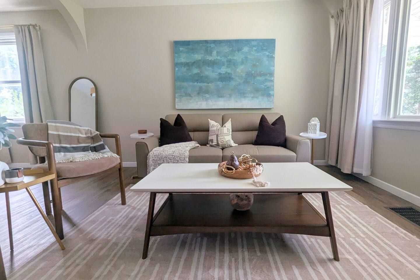 A living room with a sofa, a coffee table, a chair, a side table, and a painting on the wall.