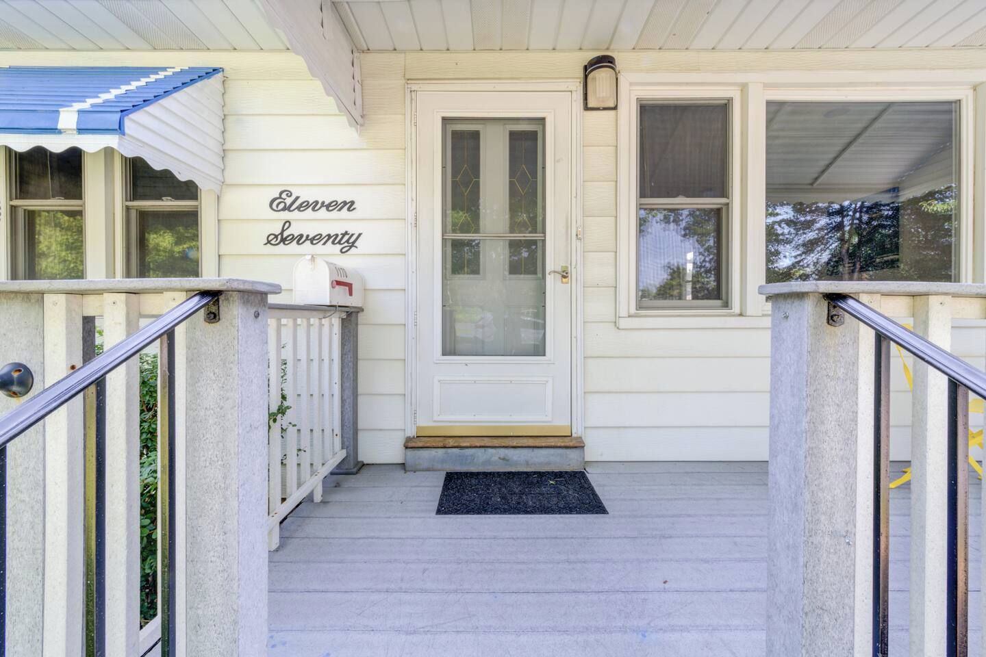 A front porch with a white door, a mailbox, and a sign reading 'Eleven Seventy'.