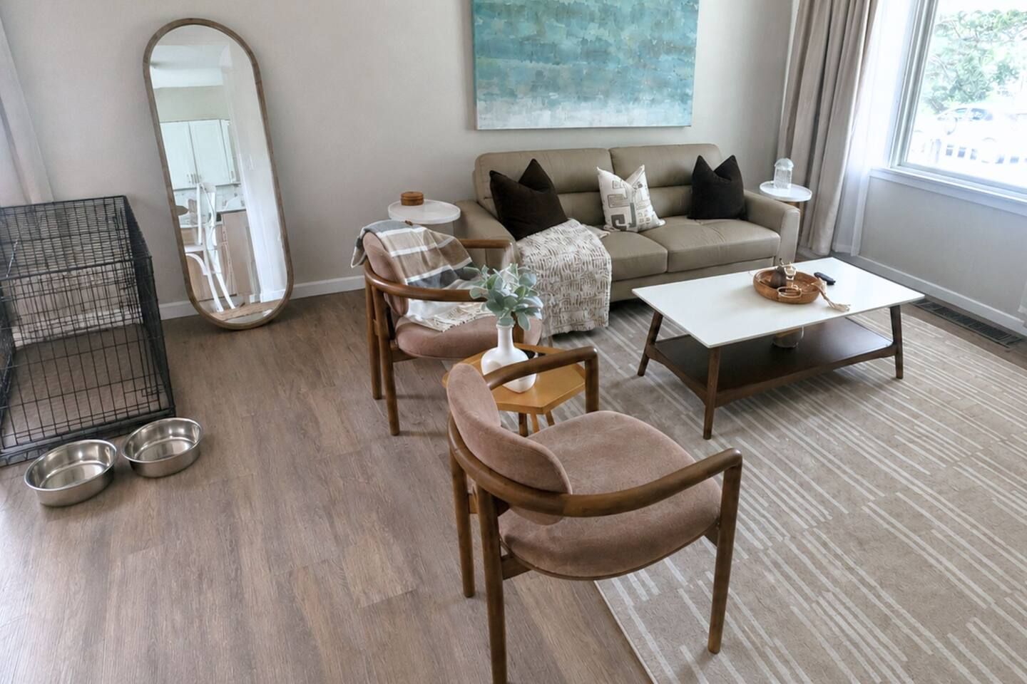 A living room with a sofa, armchairs, a coffee table, a small table with a vase, and a mirror.
