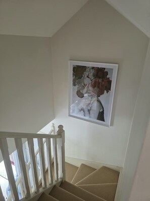 A staircase with a white railing leading to a landing where a framed artwork is displayed. - Welcome to La Maison Leura, a beautiful 3-bedroom garden retreat in the village. (Leura)