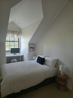 A bedroom with a bed, a desk with a computer, a window, and a painting on the wall. - Welcome to La Maison Leura, a beautiful 3-bedroom garden retreat in the village. (Leura)