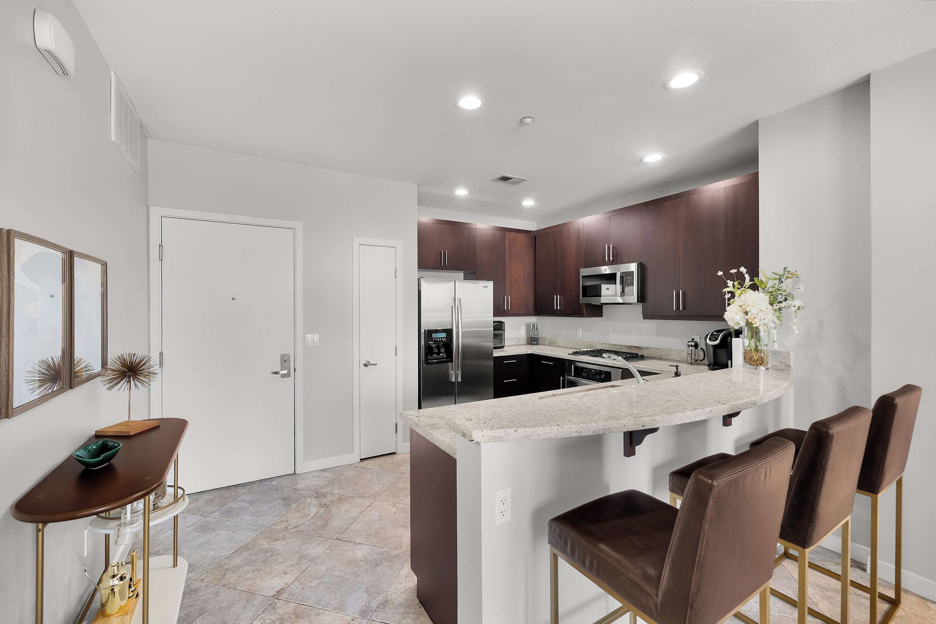 A modern kitchen with a central island, stainless steel appliances, and dark wood cabinets.