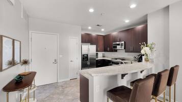 A modern kitchen with a central island, stainless steel appliances, and dark wood cabinets.
