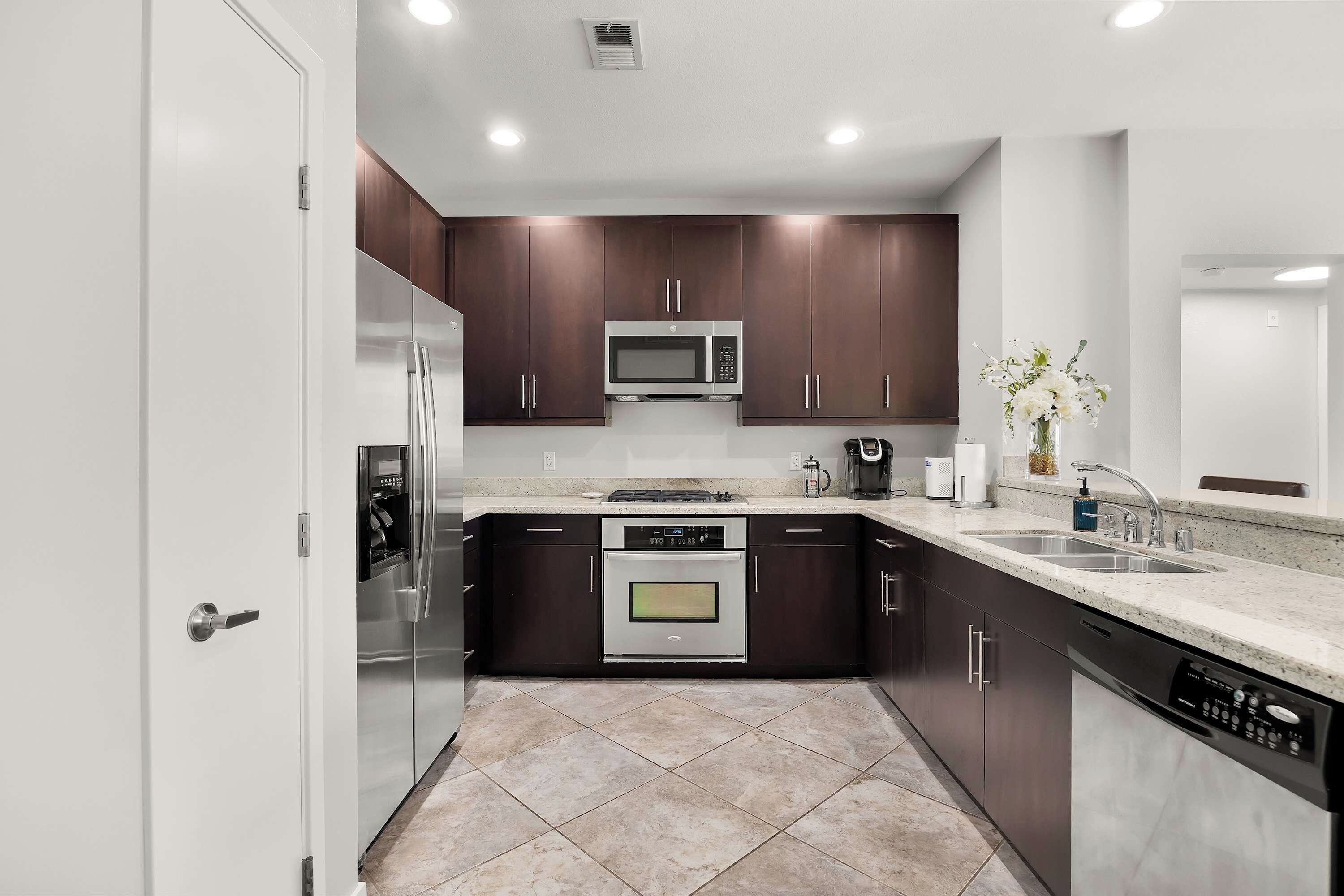 A modern kitchen with stainless steel appliances, dark cabinetry, and a tiled backsplash.