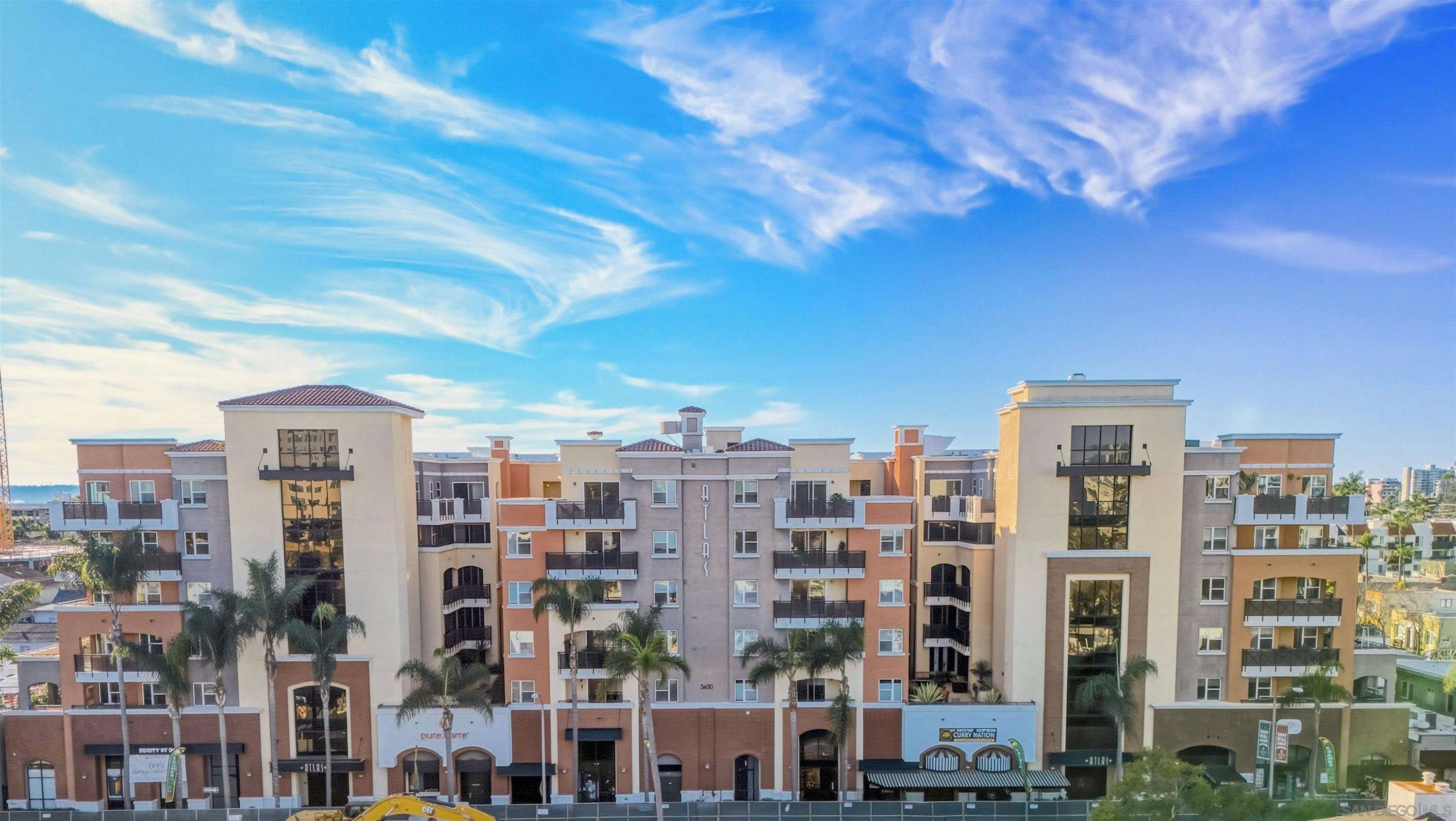 A multi-story residential building with balconies, a clear sky, and palm trees.