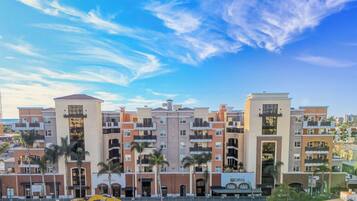 A multi-story residential building with balconies, a clear sky, and palm trees.