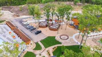 An aerial view of a resort with a pool, outdoor seating, and a fire pit area.