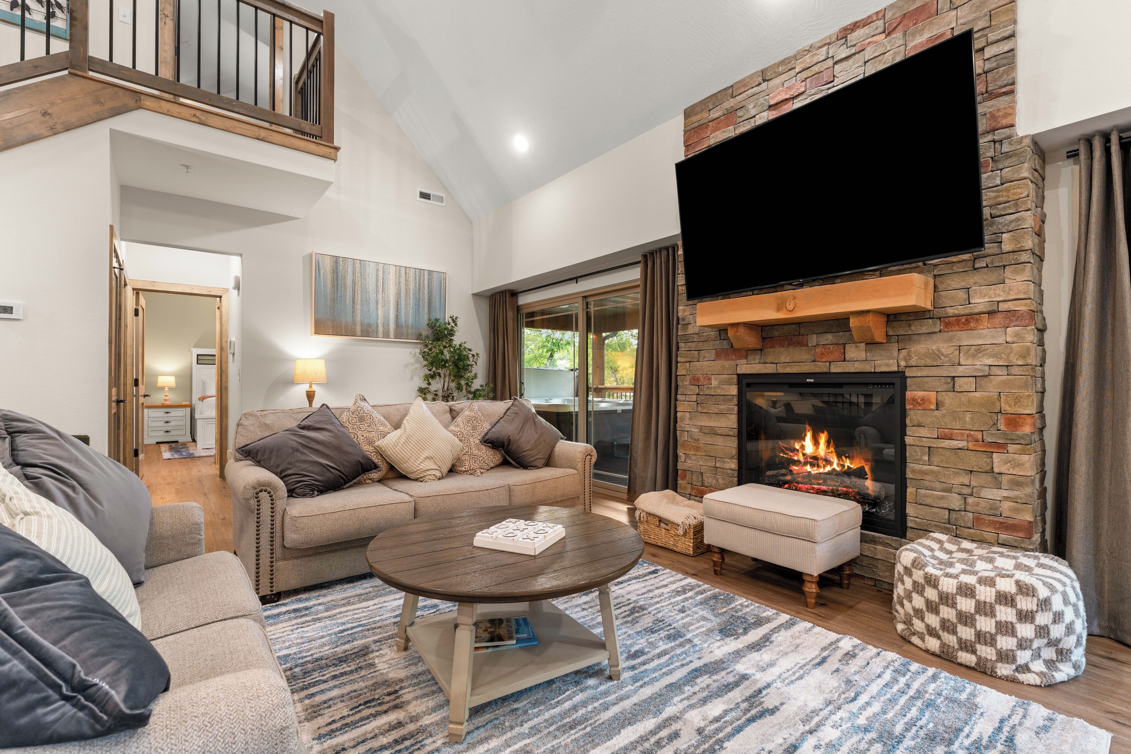 A modern living room with a stone fireplace, a flat-screen TV, a sofa, and a coffee table.
