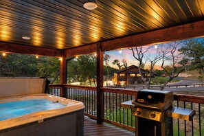A wooden deck with a hot tub and a grill, overlooking a residential area with houses and trees. - New Listing 3b/3b Cabin in Tall Timers Camp, steps away from many amenities! (Hollister)